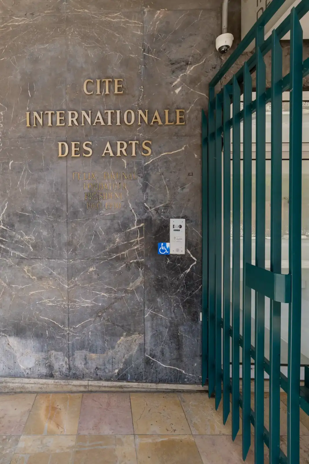 Mur en marbre gris avec des lettres dorées de la Cité internationale des arts.