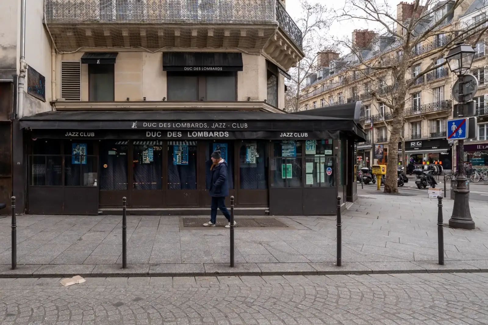 Une personne marche devant la façade du célèbre club de jazz parisien Duc des Lombards.