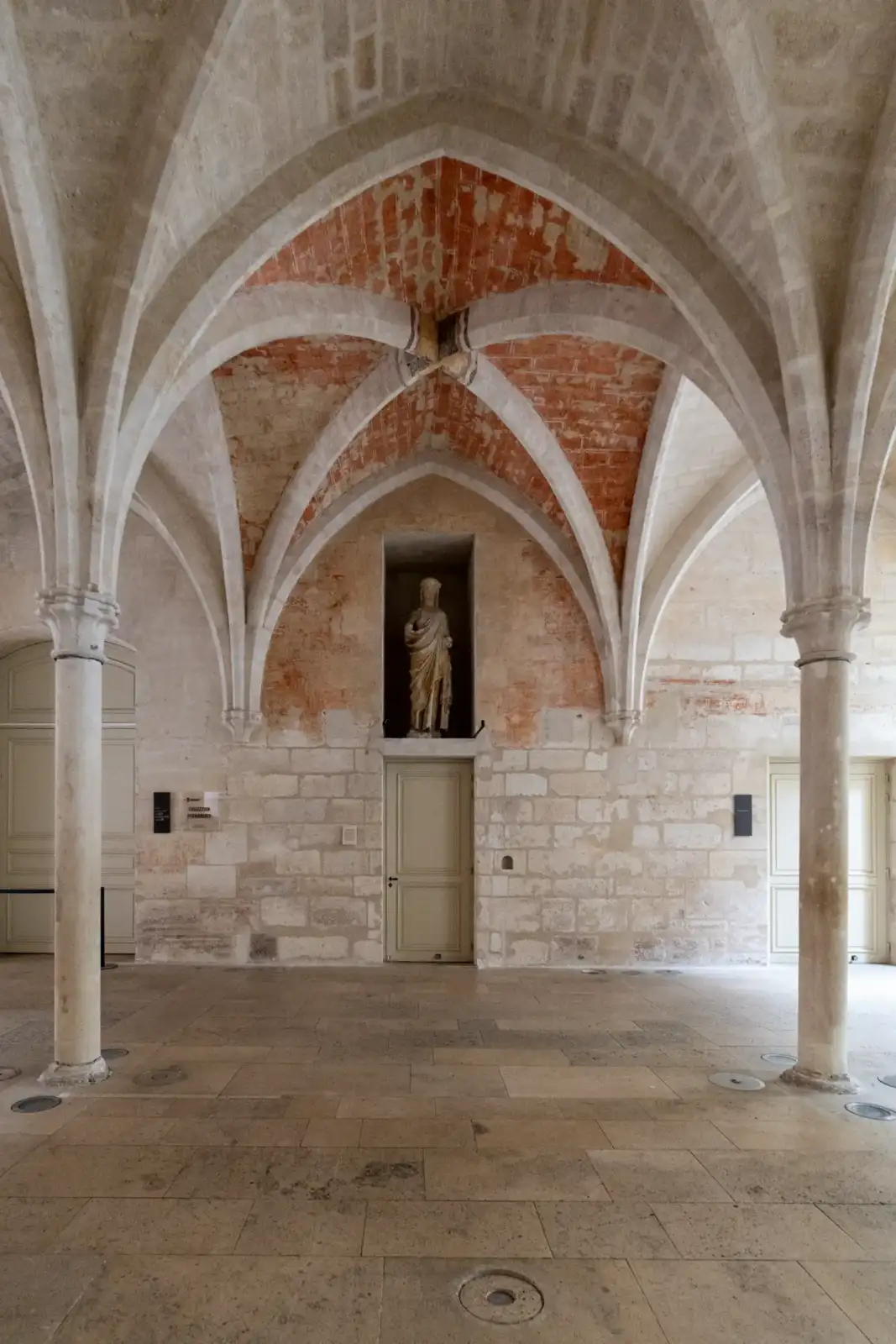 Voûtes d ogives en brique et pierre soutenues par deux colonnes en marbre beige.