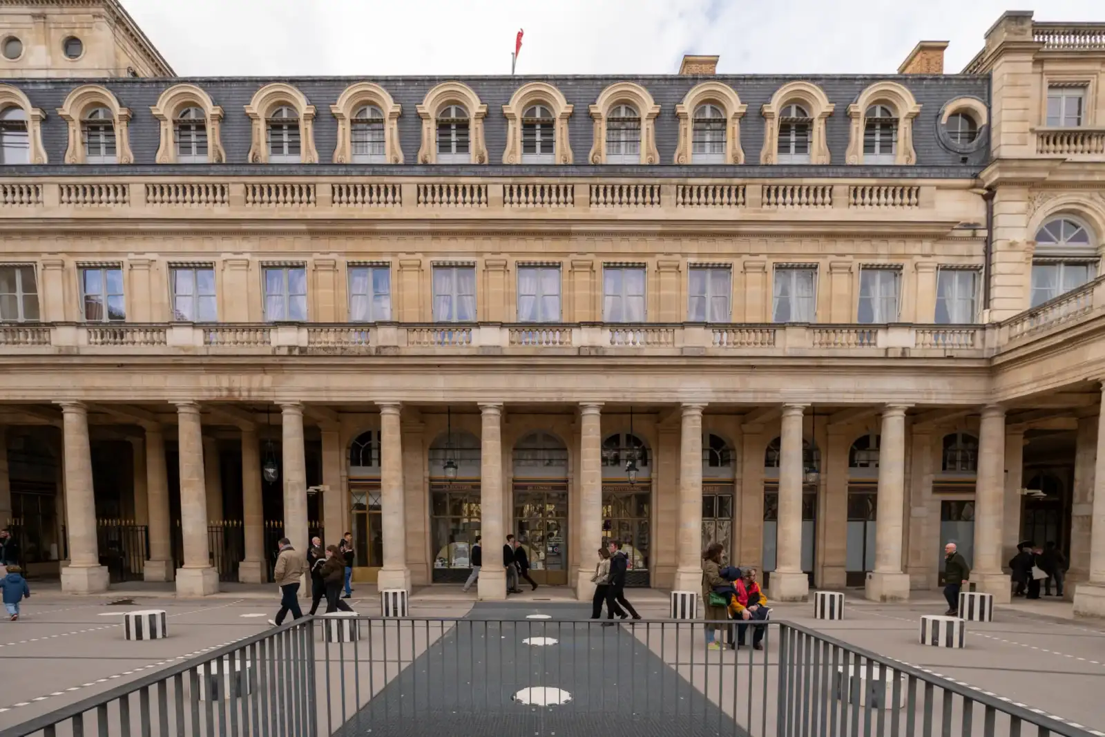 La façade classique du Conseil constitutionnel à Paris avec des passants sur la place.