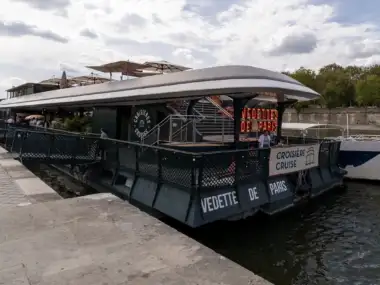 Un bateau de croisière Vedettes de Paris est amarré sur un quai.