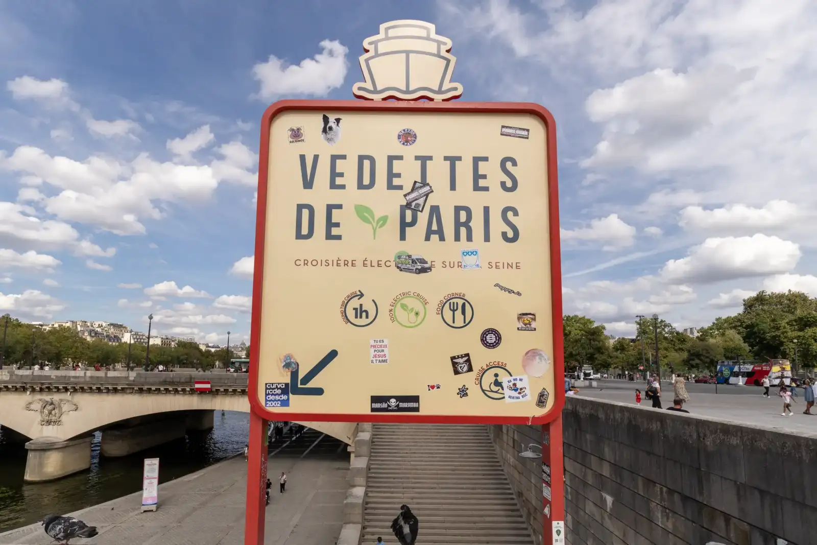 Un panneau d'affichage Vedettes de Paris se dresse au bord de la Seine.