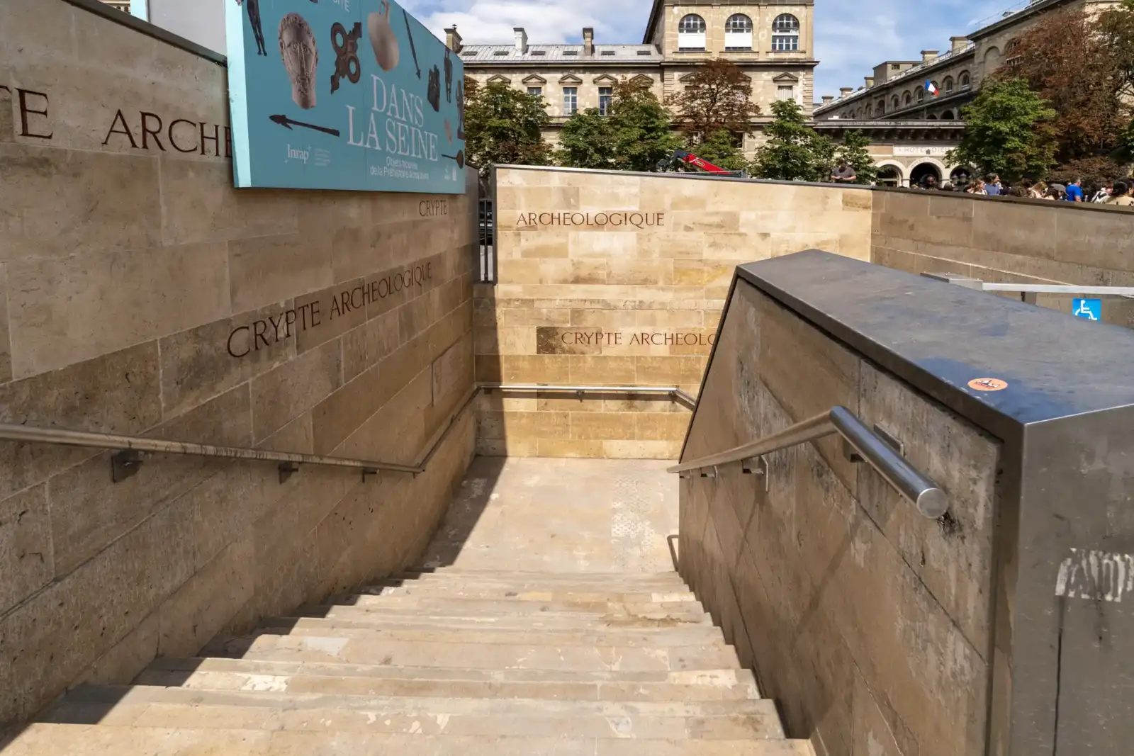 Entrée extérieure de la crypte archéologique de Paris avec une signalétique en pierre claire.