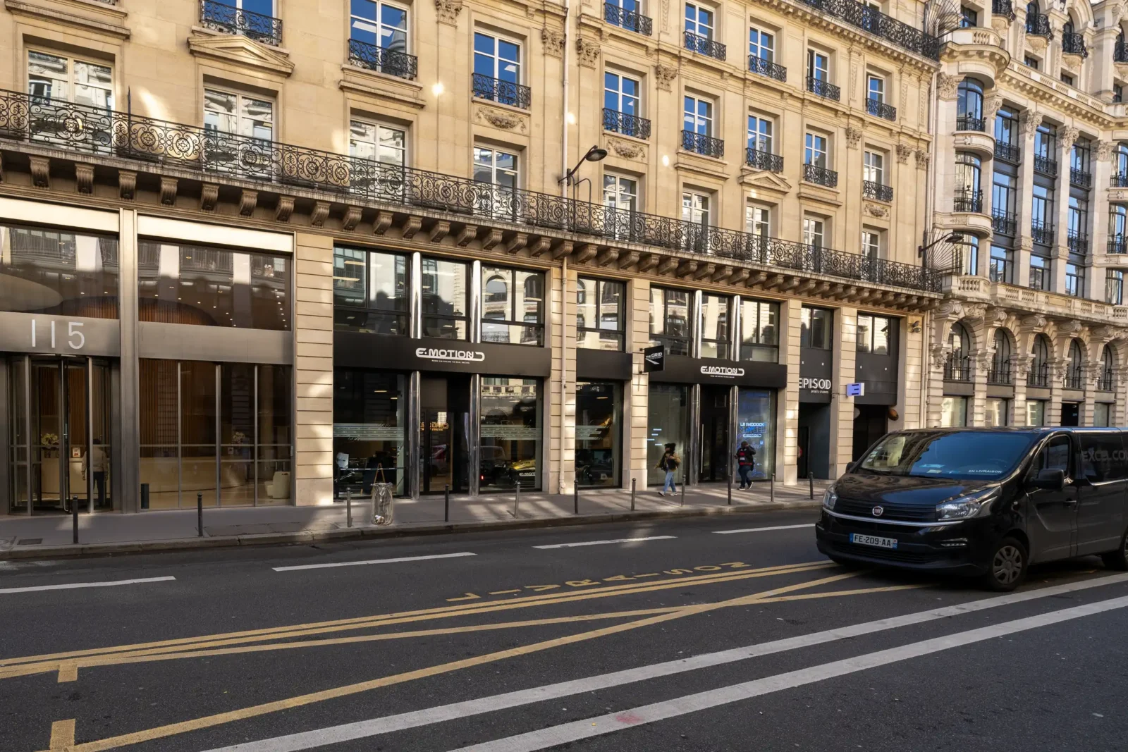 Façade d'un centre de simulation automobile E-Motion située dans une rue parisienne ensoleillée.
