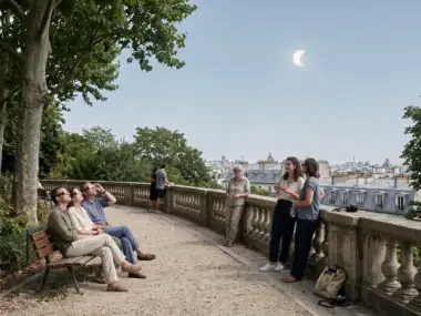 Des spectateurs admirent une éclipse solaire partielle au-dessus des toits de Paris.