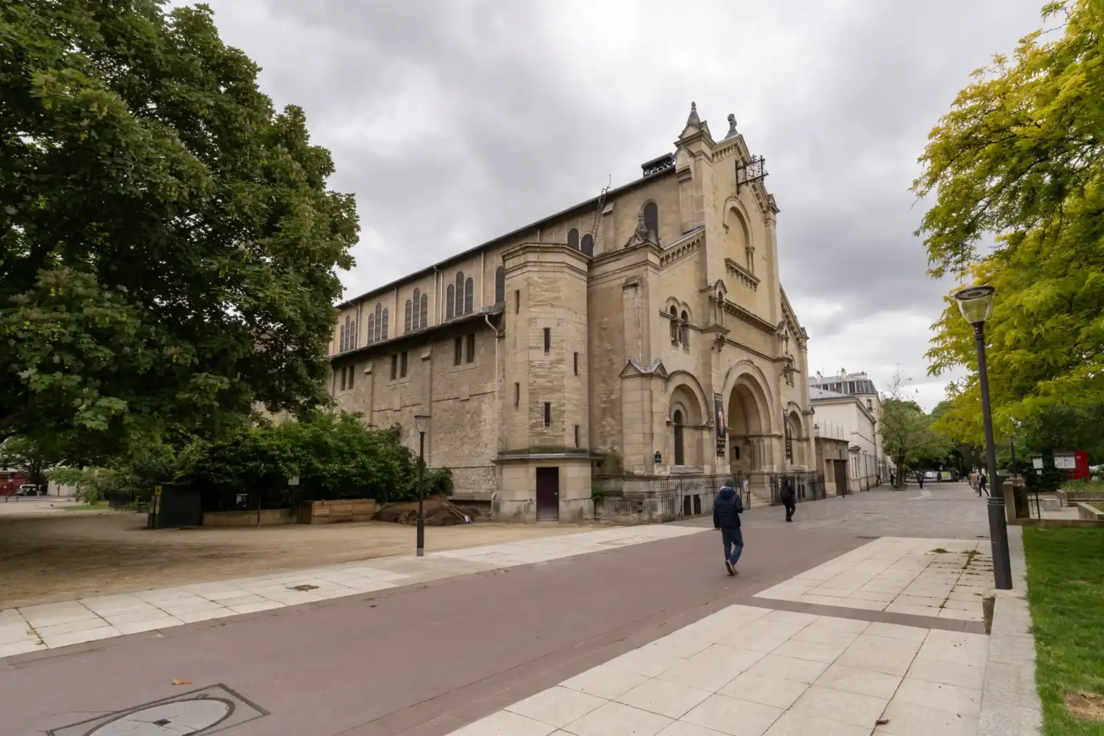 Vue extérieure de l église Notre Dame du Travail avec des passants sous un ciel gris.