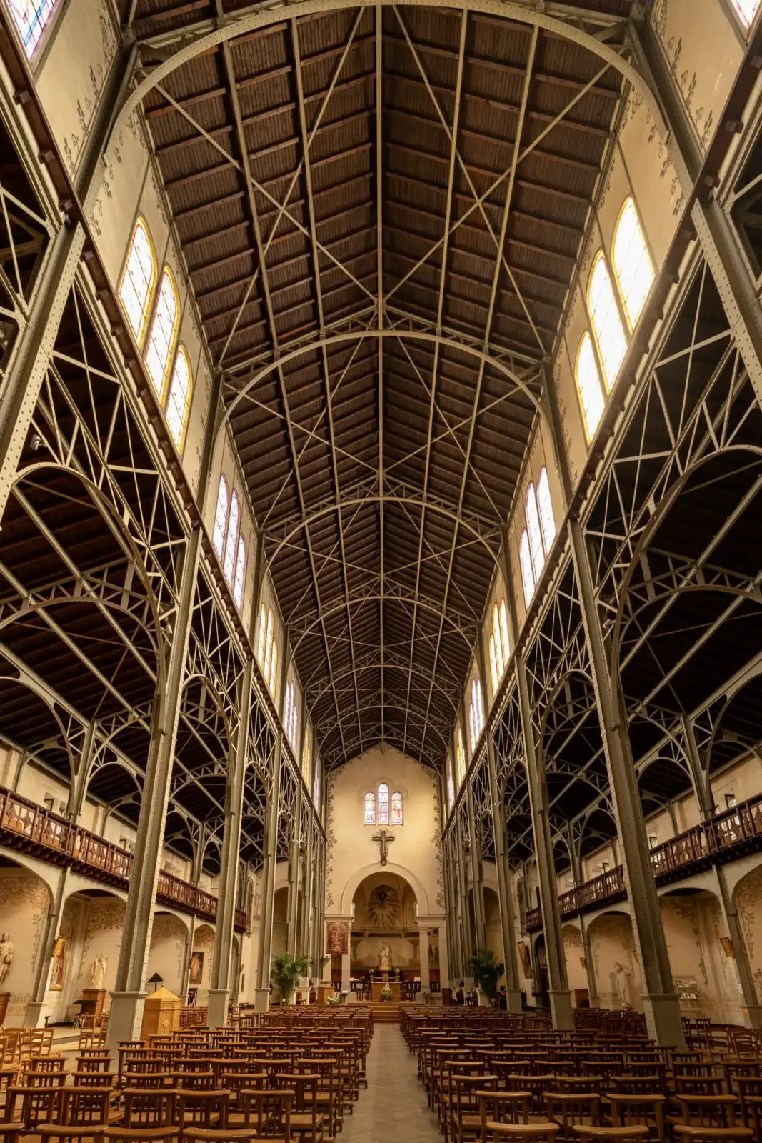 Vue intérieure de l'église Notre-Dame-du-Travail avec sa structure métallique apparente et ses rangées de bancs.