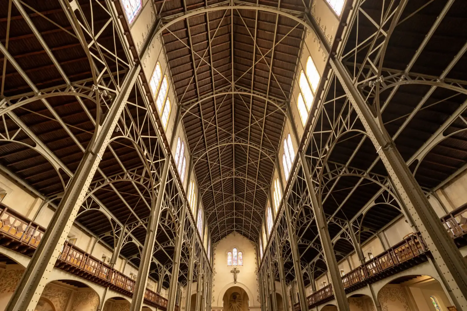 Vue en contre-plongée de la vaste charpente métallique intérieure de l'église Notre-Dame-du-Travail à Paris.