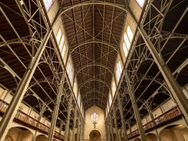 Vue en contre-plongée de la vaste charpente métallique intérieure de l'église Notre-Dame-du-Travail à Paris.
