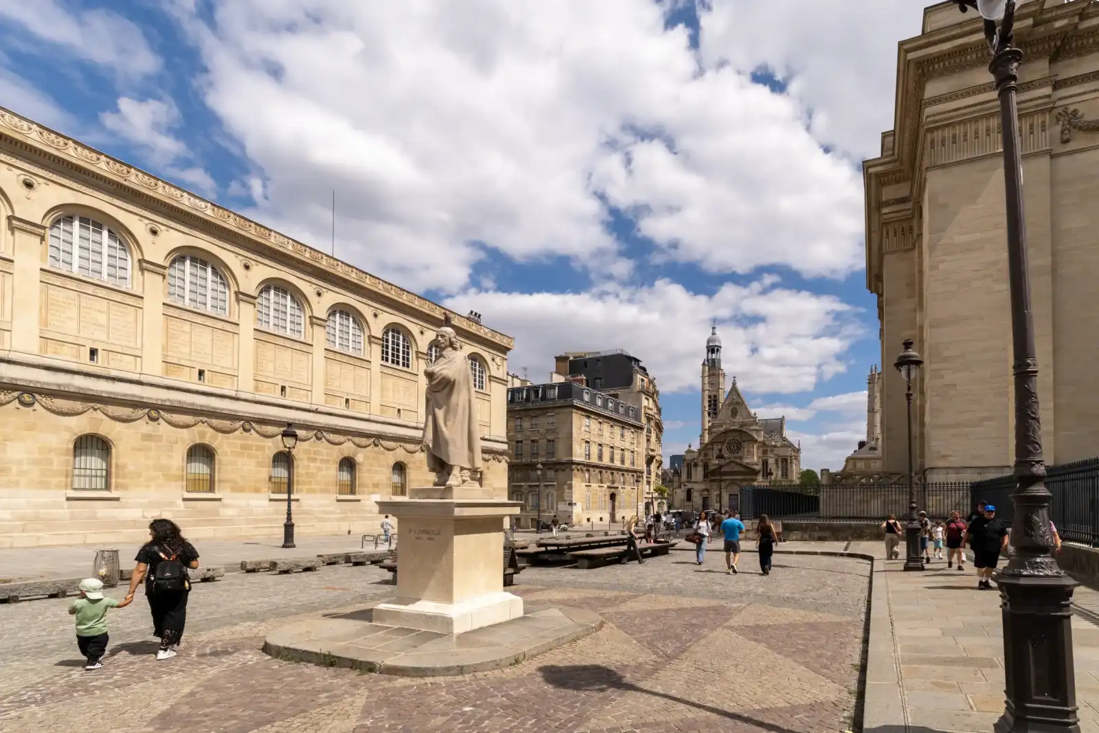 Une statue de Pierre Corneille se dresse fièrement sur une place pavée parisienne.
