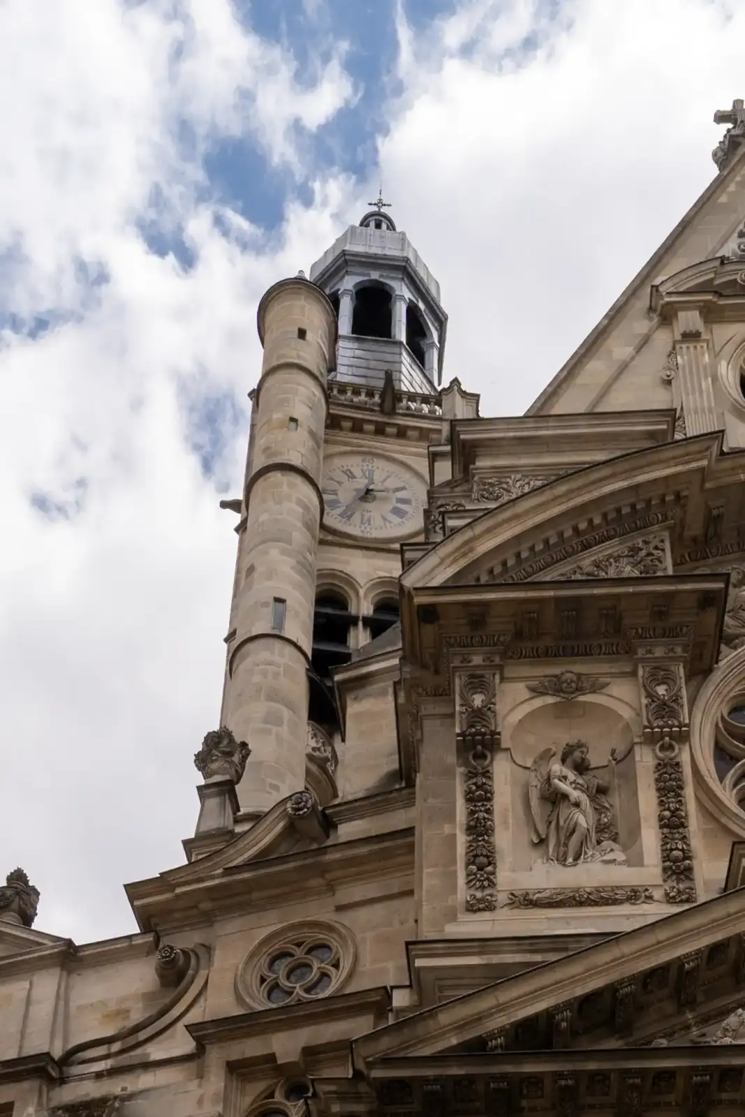 Façade de pierre sculptée et clocher de l'église Saint-Étienne-du-Mont sous un ciel nuageux.