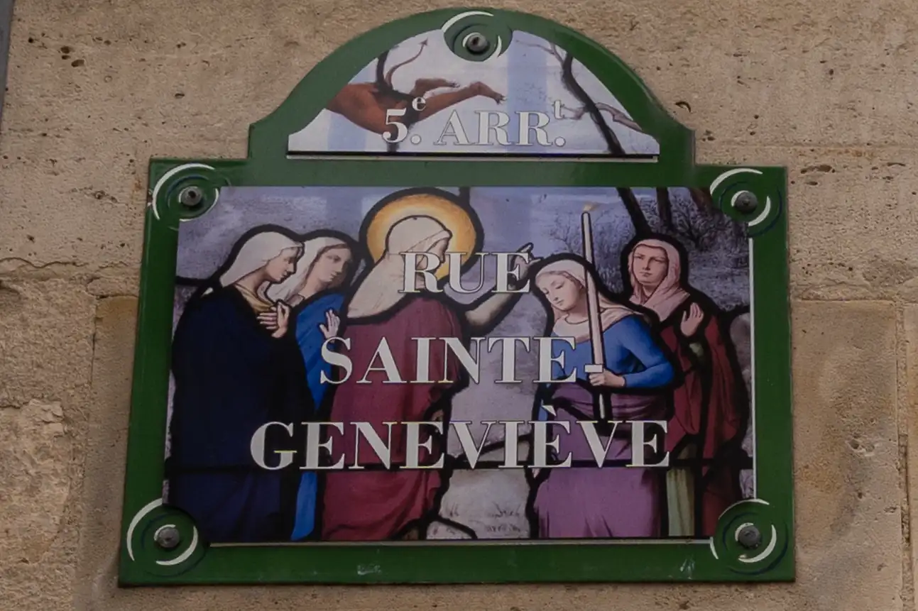Une plaque de rue parisienne verte et blanche illustrée de femmes voilées.