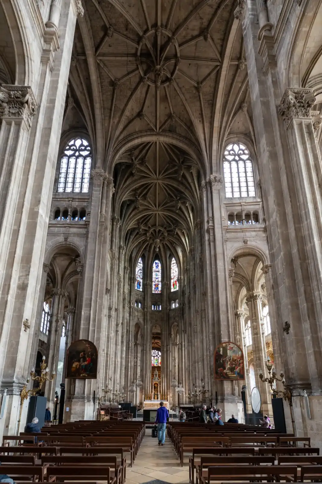 Vue intérieure majestueuse de l'église Saint-Eustache avec ses voûtes gothiques et ses bancs alignés.