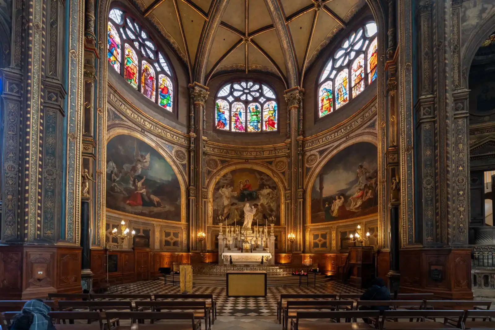 L'intérieur richement décoré de l'église Saint-Eustache présente un autel central sous des vitraux.