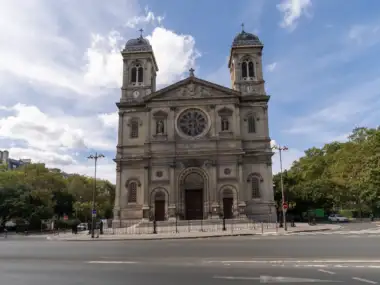 La façade symétrique et monumentale de l église Saint François Xavier sous un ciel nuageux.