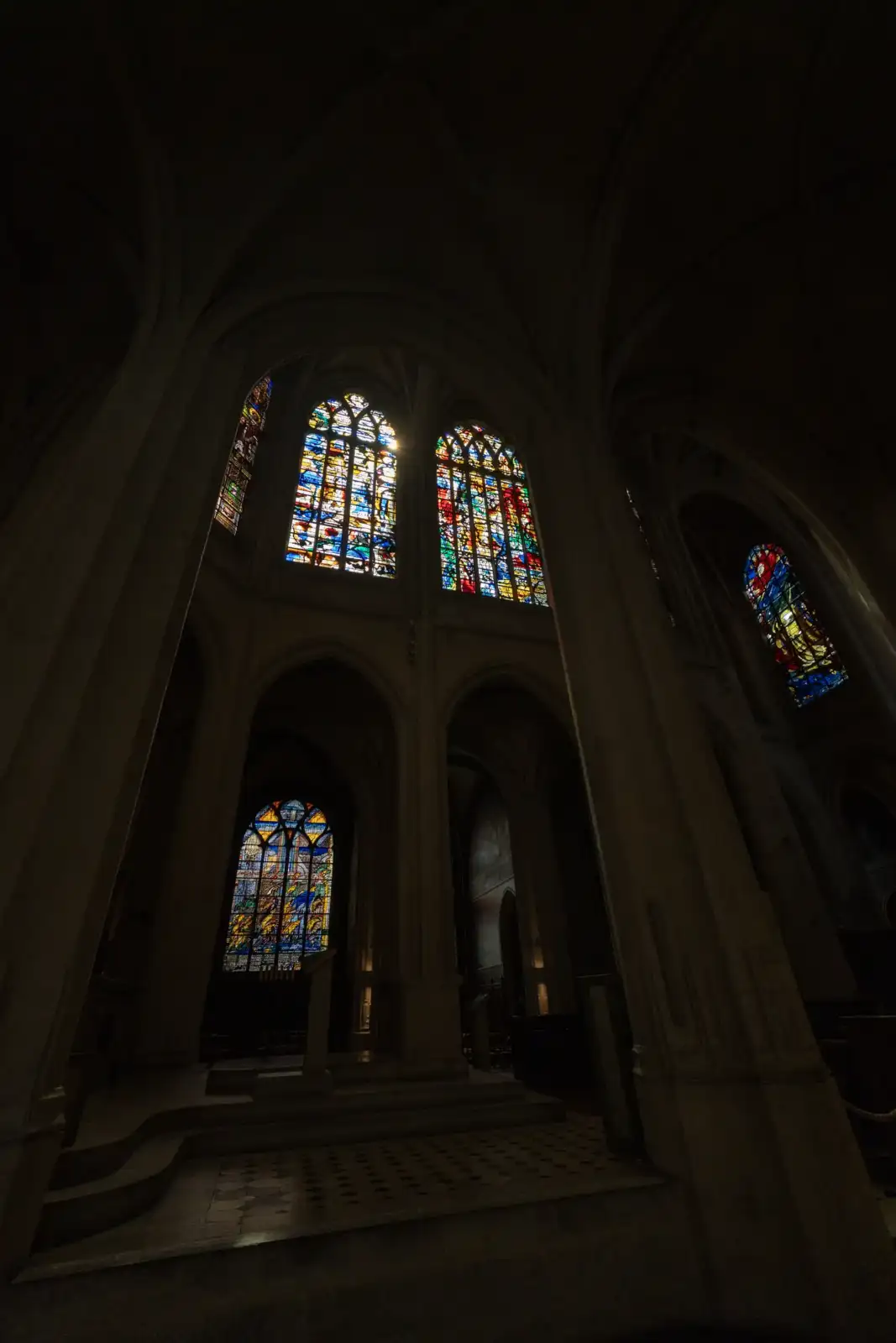 Des vitraux colorés illuminent l'intérieur sombre et gothique de l'église Saint-Gervais.