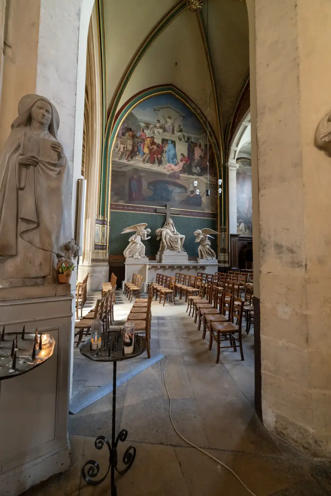 Vue intérieure de l'église avec des rangées de chaises en bois et des statues.