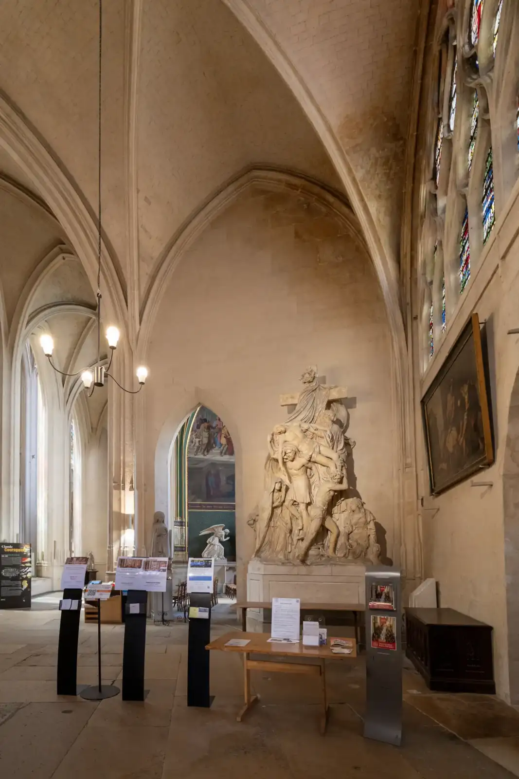 Intérieur gothique de l'église Saint-Gervais-Saint-Protais à Paris avec une statue monumentale et des vitraux.