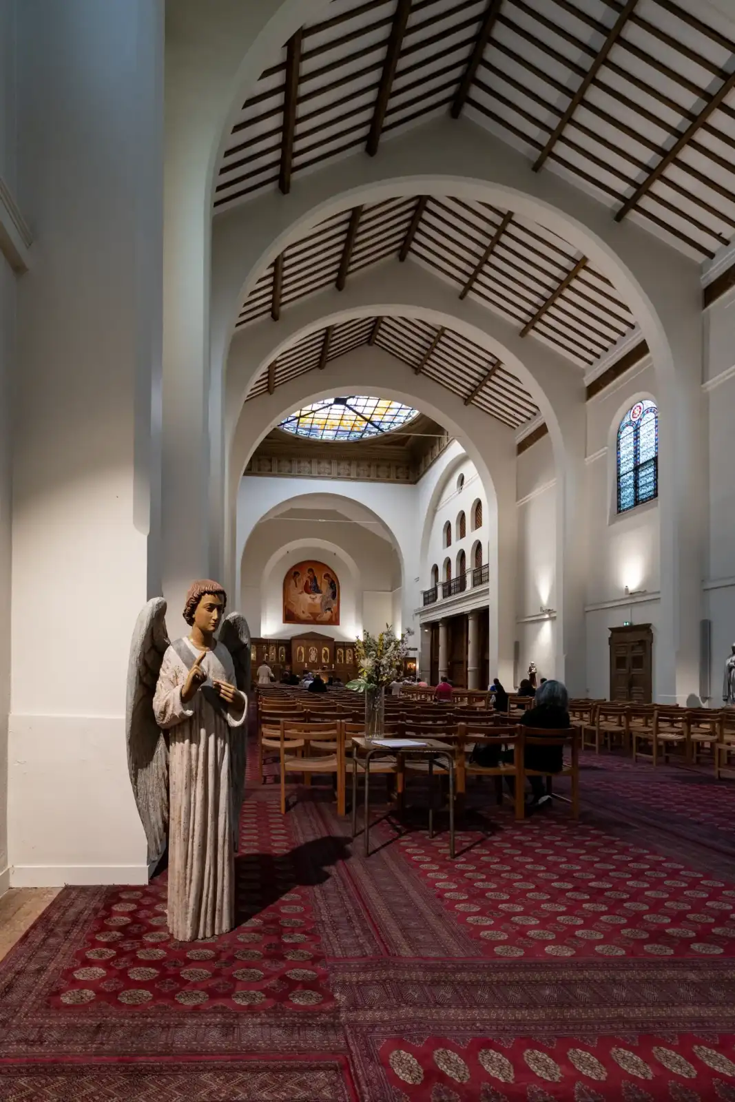 Statue d ange au premier plan dans l interieur lumineux d une grande eglise parisienne.
