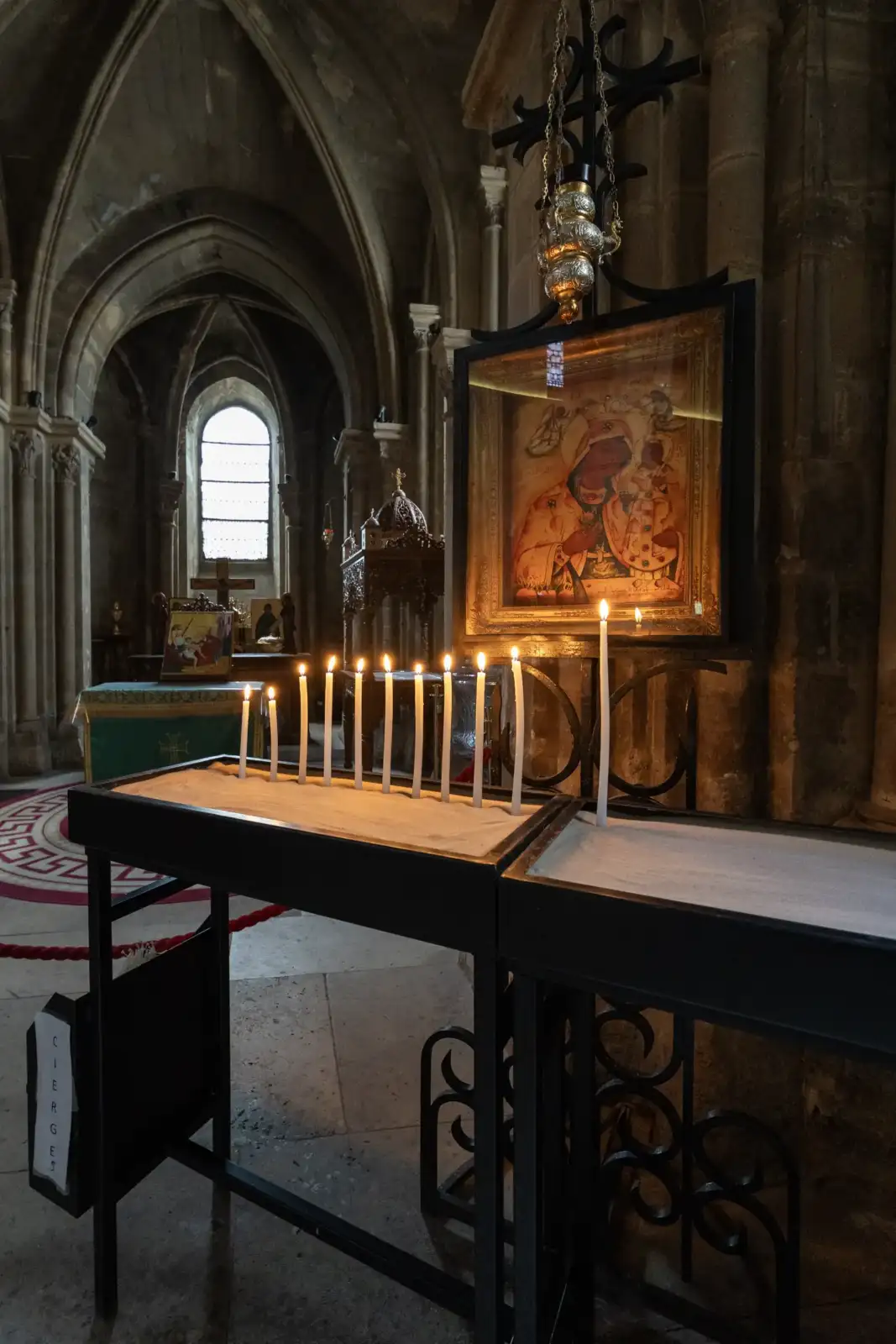 Des cierges allumés brillent devant une icône religieuse dans une église ancienne.