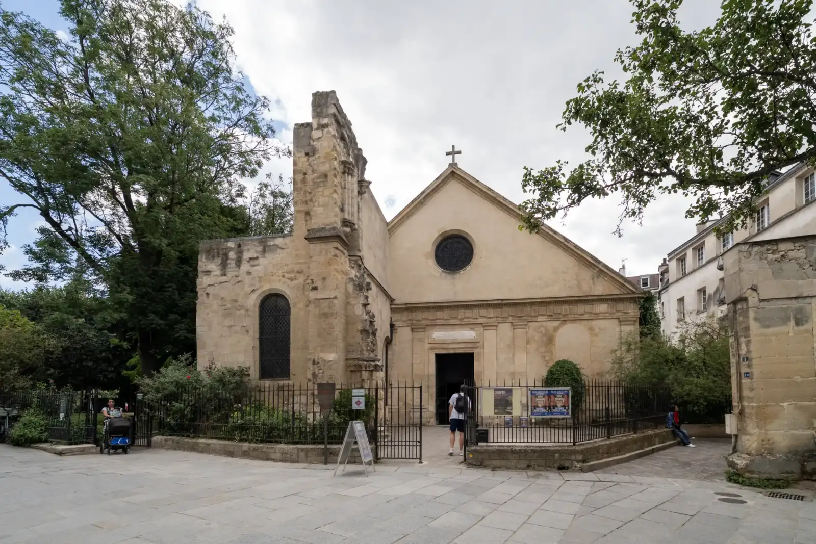 Façade de l'église Saint-Julien-le-Pauvre à Paris, entourée de verdure et de pavés.