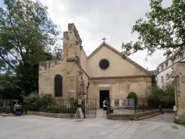 Façade de l'église Saint-Julien-le-Pauvre à Paris, entourée de verdure et de pavés.
