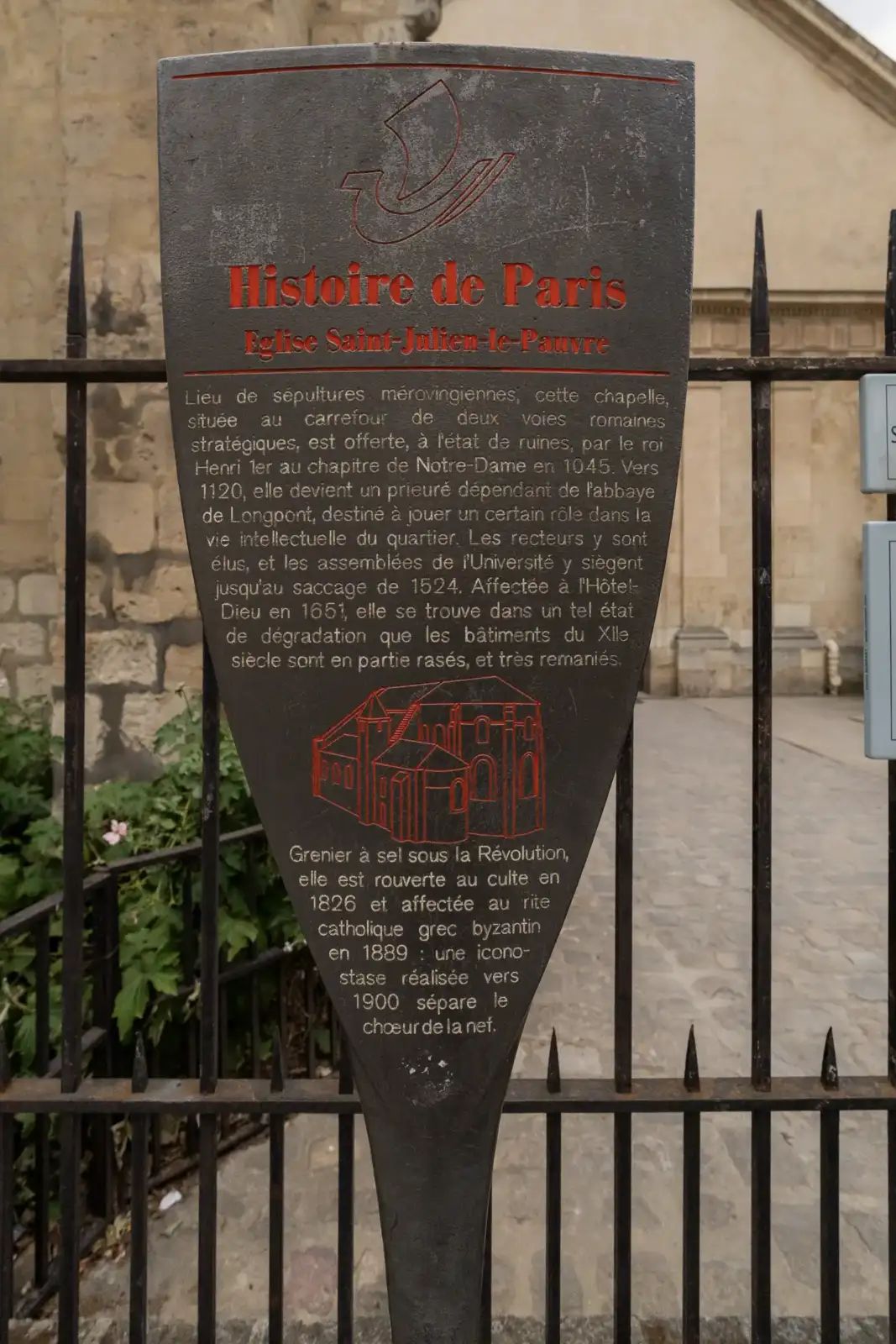 Un panneau d information métallique Historire de Paris est fixé sur une grille.