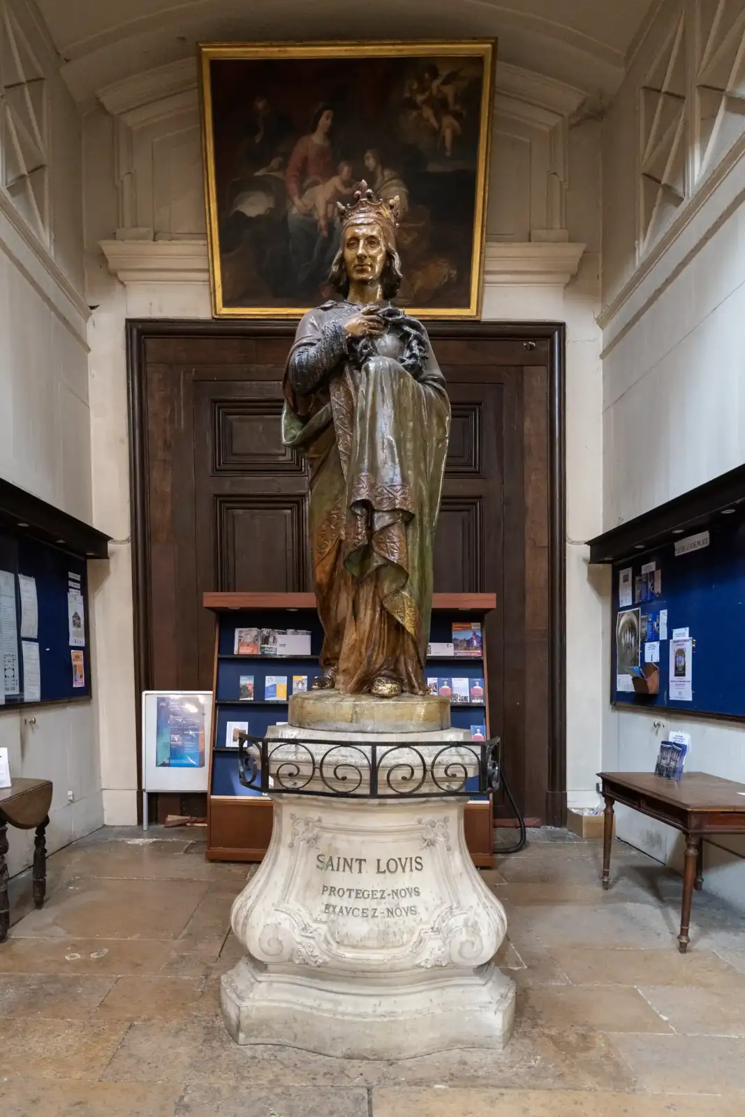 Une statue de Saint Louis portant une couronne se dresse dans une église parisienne.