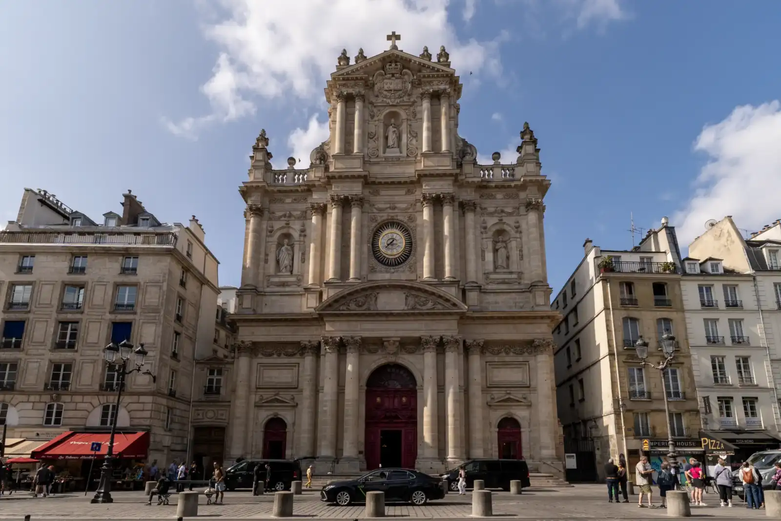 La majestueuse façade baroque de l’église Saint-Paul-Saint-Louis s'élève sous un ciel bleu partiellement nuageux à Paris.