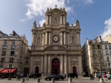 La majestueuse façade baroque de l’église Saint-Paul-Saint-Louis s'élève sous un ciel bleu partiellement nuageux à Paris.