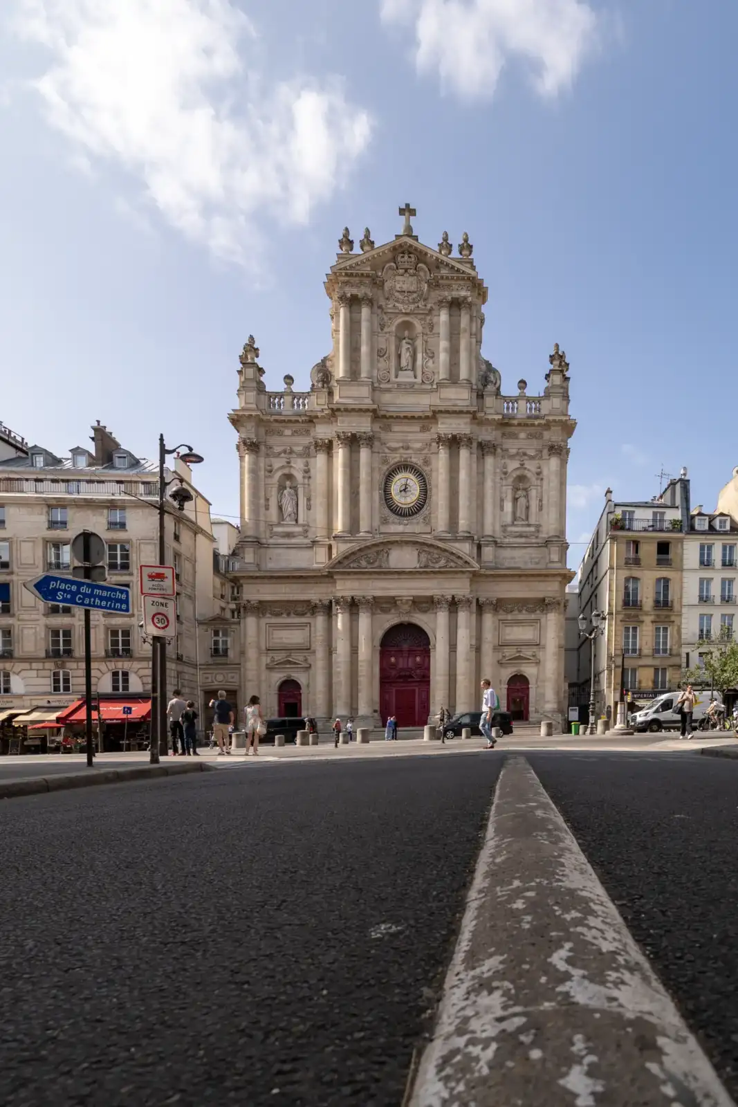 Façade baroque de l’église Saint-Paul-Saint-Louis sous un ciel bleu avec des passants.