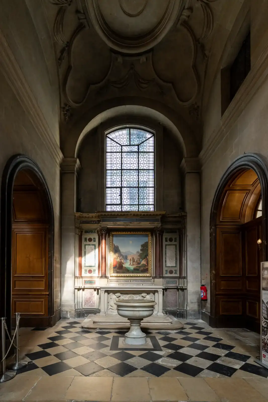Un autel en pierre et un tableau sous une grande verrière de l'église.