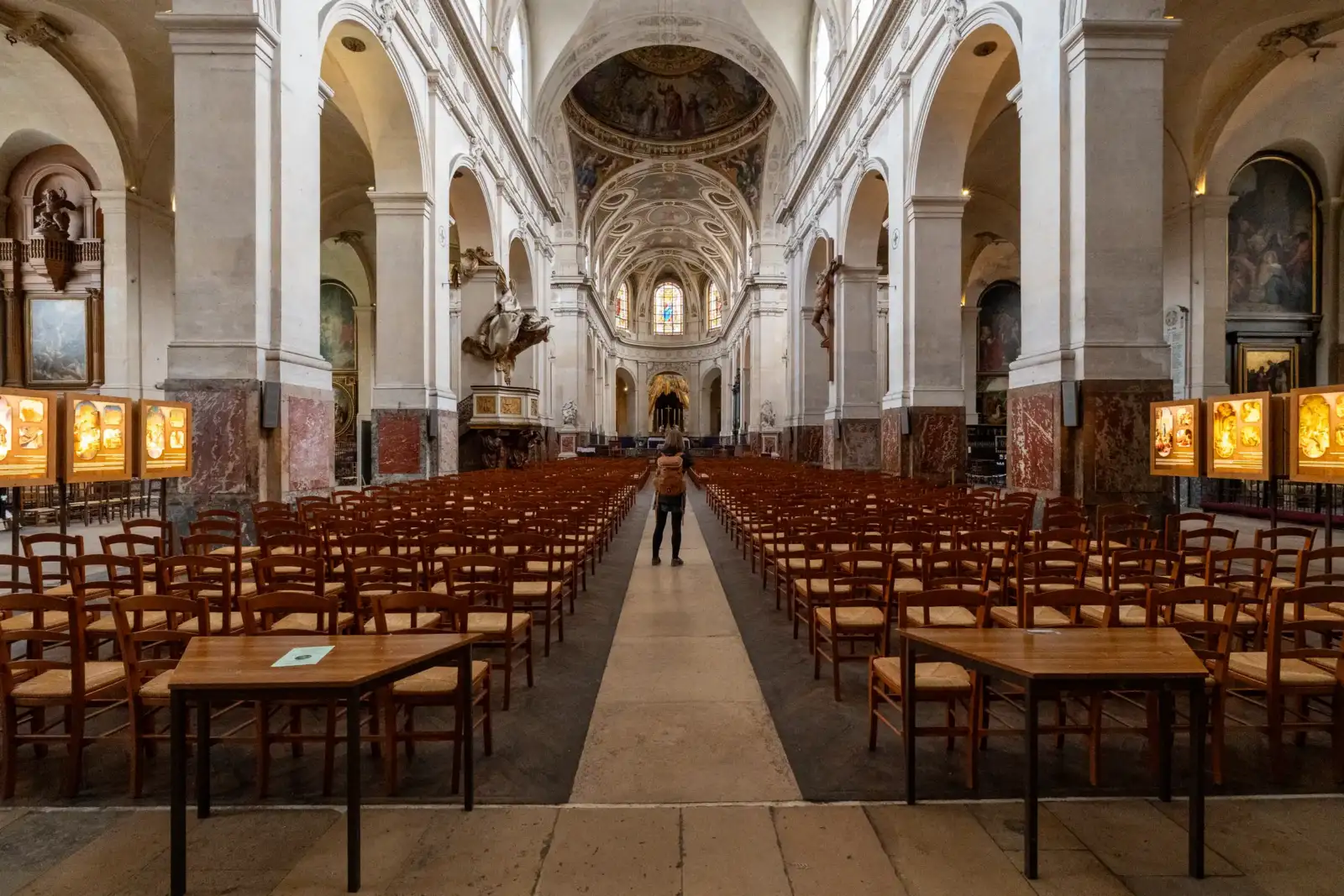 Une personne se tient dans l'allée centrale de l'église Saint-Roch richement décorée à Paris.