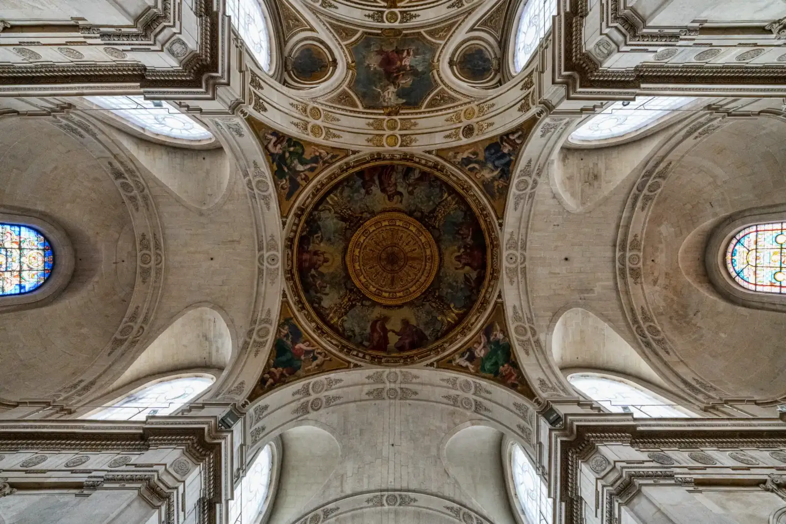 Vue en contre-plongée de la coupole ornée et voûtée de l'église Saint-Roch à Paris.