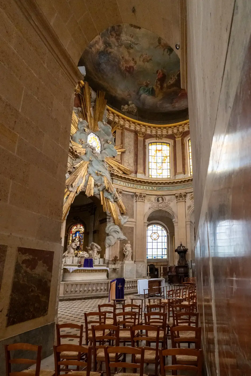 Vue intérieure de l'église Saint-Roch avec son autel doré et ses chaises alignées.