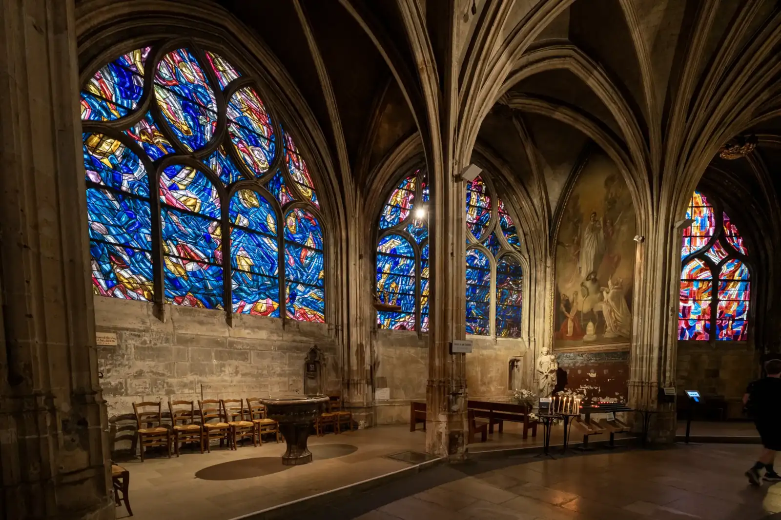 Intérieur gothique de l'église Saint-Séverin avec des vitraux colorés et des voûtes en pierre.