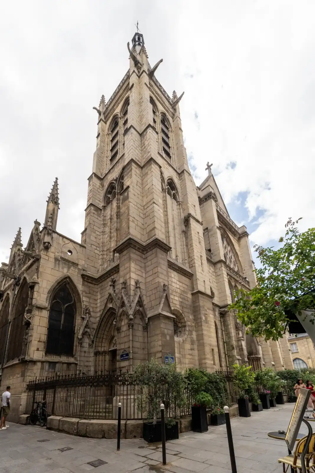 Une vue en contre-plongée de l'église Saint-Séverin à Paris depuis une rue piétonne.