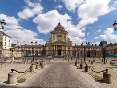 Vue extérieure de l'église du Val-de-Grâce à Paris sous un ciel nuageux.