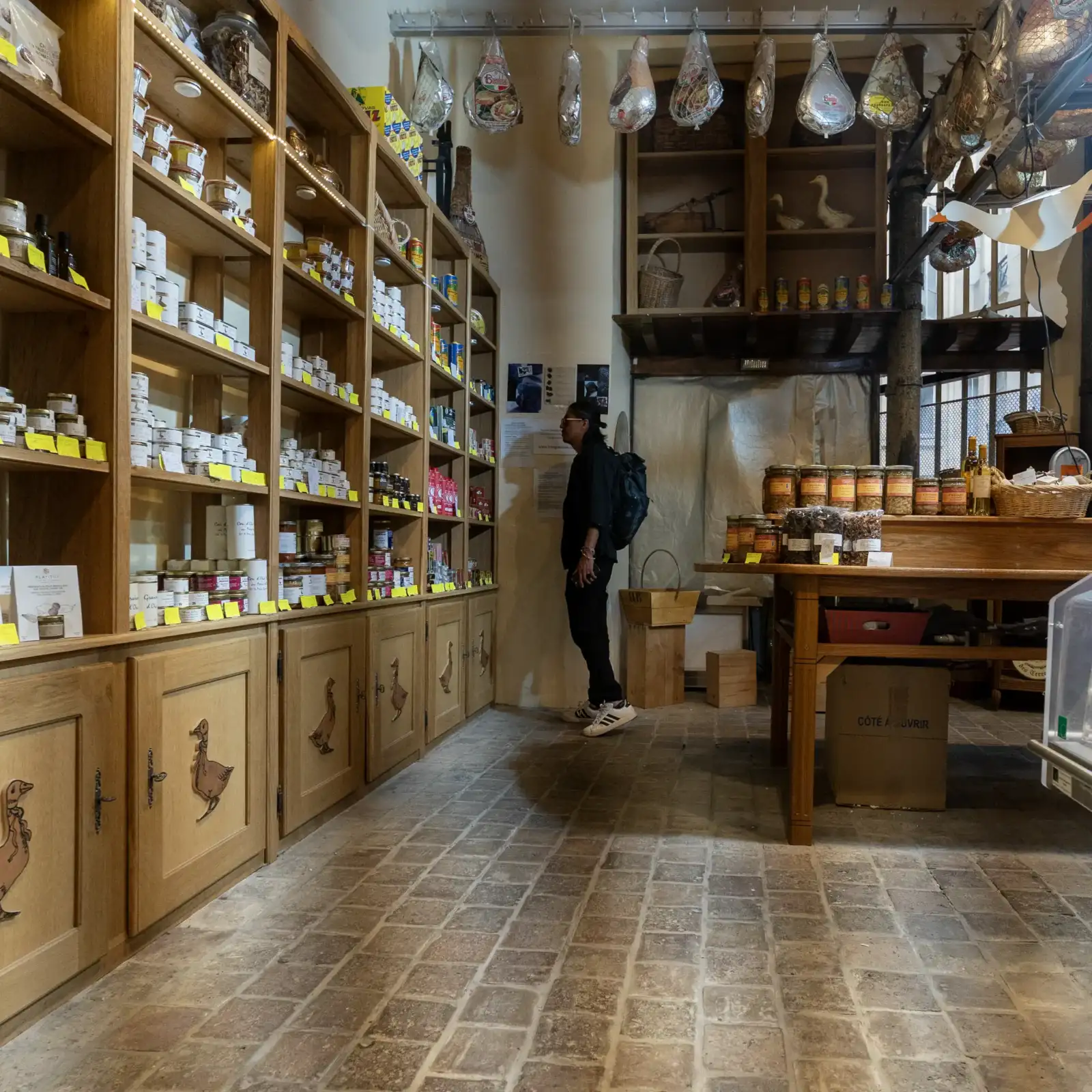 Une personne regarde les étagères remplies de produits de luxe dans une épicerie fine.