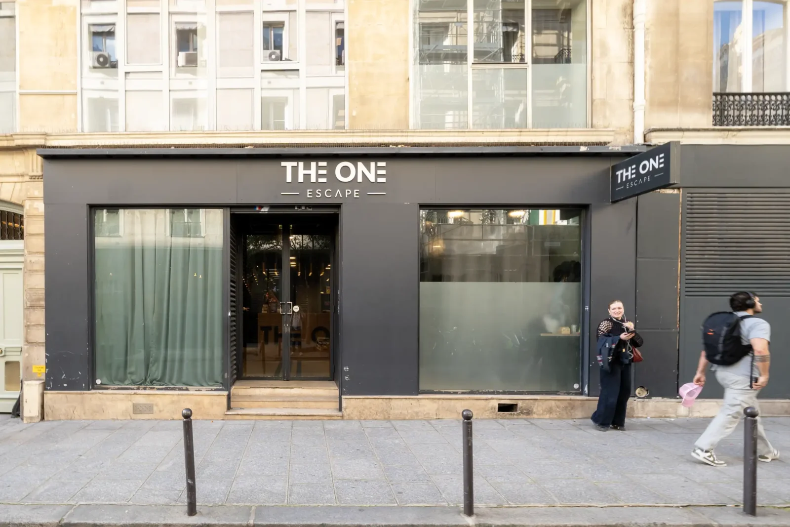 Façade noire moderne de l'enseigne The One Escape située dans une rue parisienne.