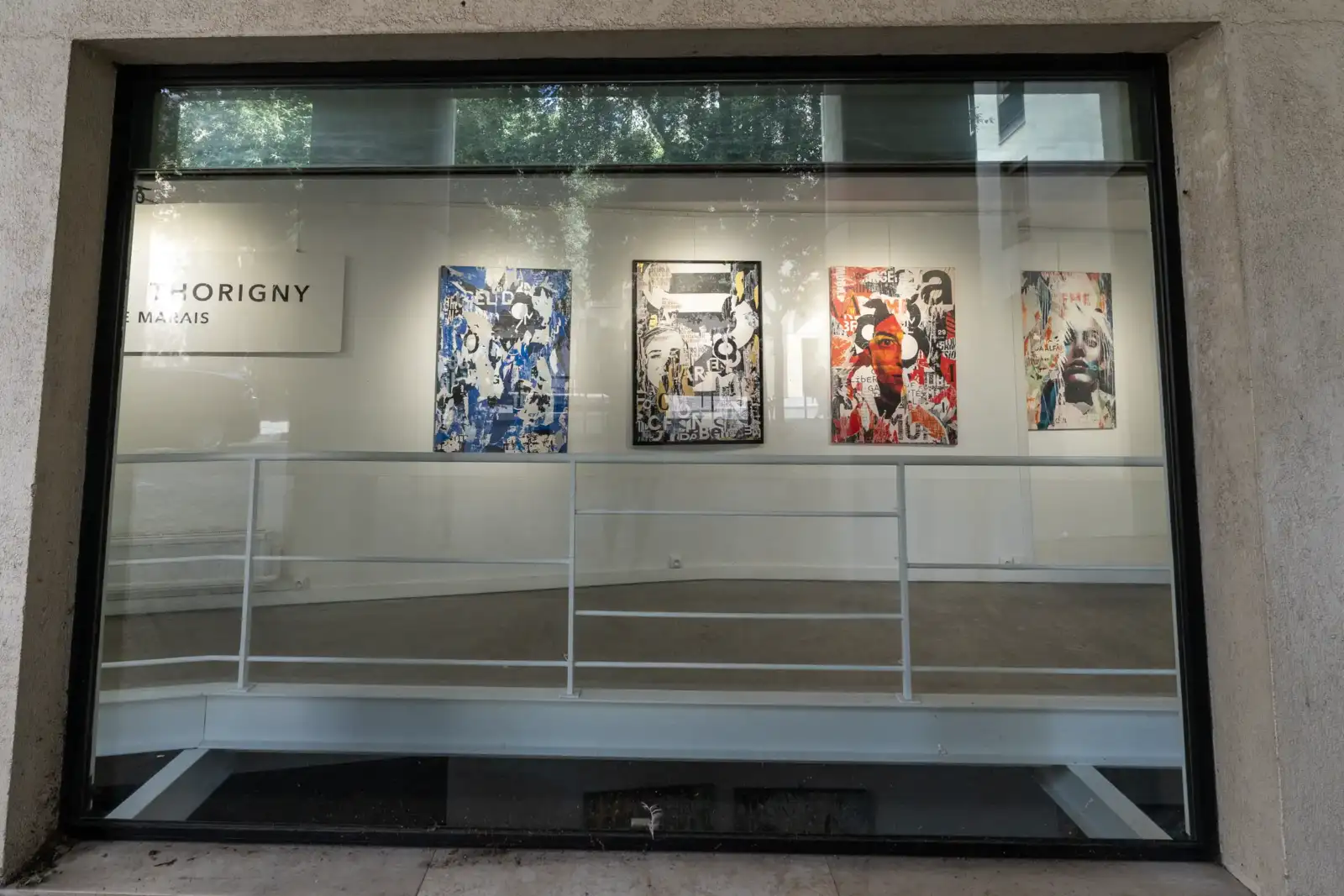 Une vitrine d exposition parisienne présente quatre tableaux d art contemporain sur fond blanc.