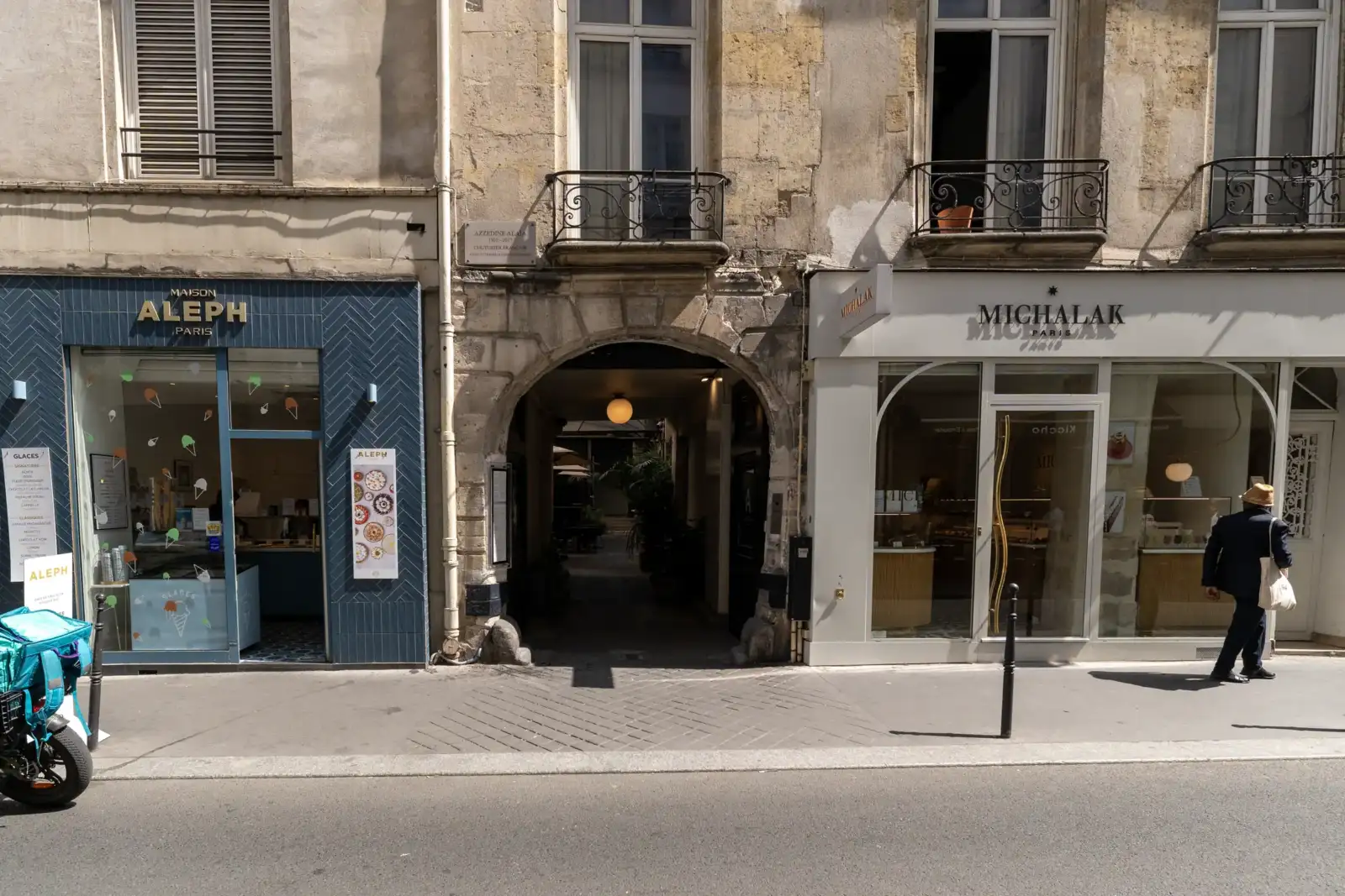 Facade ensoleillée de la Fondation Azzedine Alaïa à Paris, encadrée par deux charmantes boutiques.