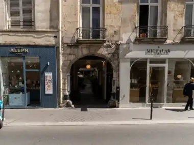 Facade ensoleillée de la Fondation Azzedine Alaïa à Paris, encadrée par deux charmantes boutiques.