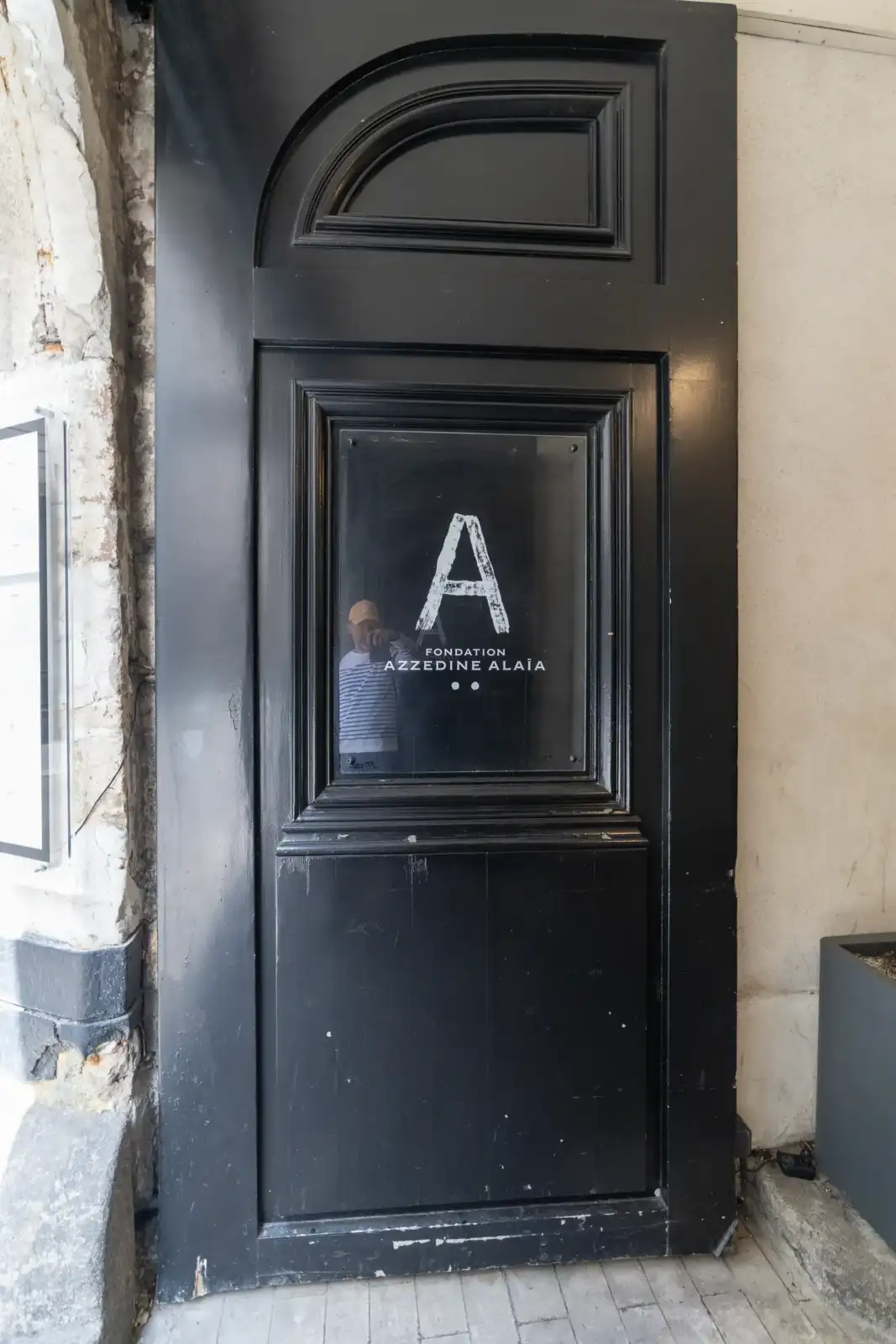 Une grande porte noire avec un panneau en verre signalétique de la Fondation Azzedine Alaia.