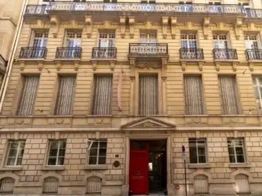 Façade haussmannienne beige de la Fondation Custodia avec une grande porte rouge au rez-de-chaussée.