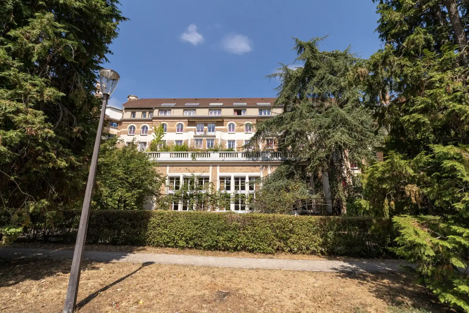 Façade de la Fondation des États-Unis à Paris encadrée par de grands arbres verdoyants.