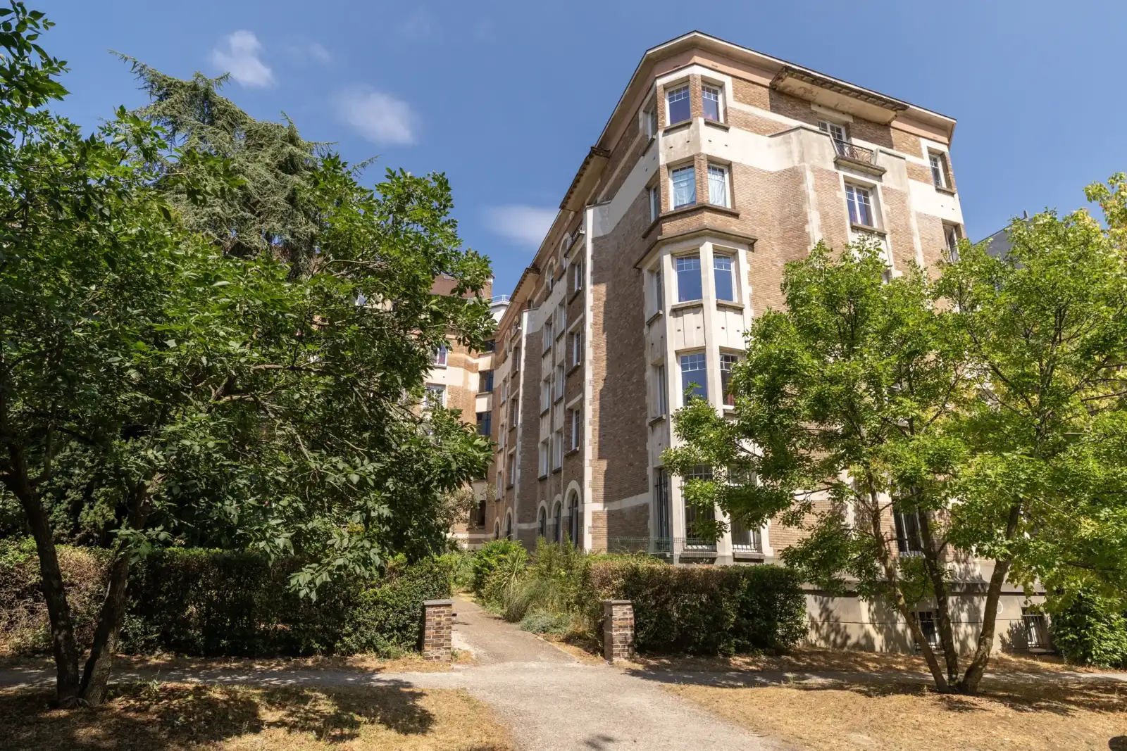 Façade ensoleillée de la Fondation des États-Unis à Paris, entourée de grands arbres verts.