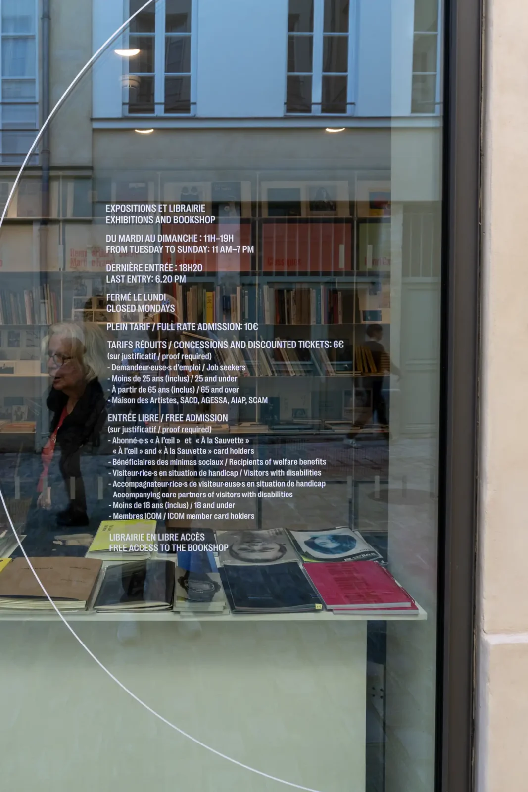 Vitrine de la Fondation Henri Cartier-Bresson affichant des informations pratiques sur fond de bibliothèque.