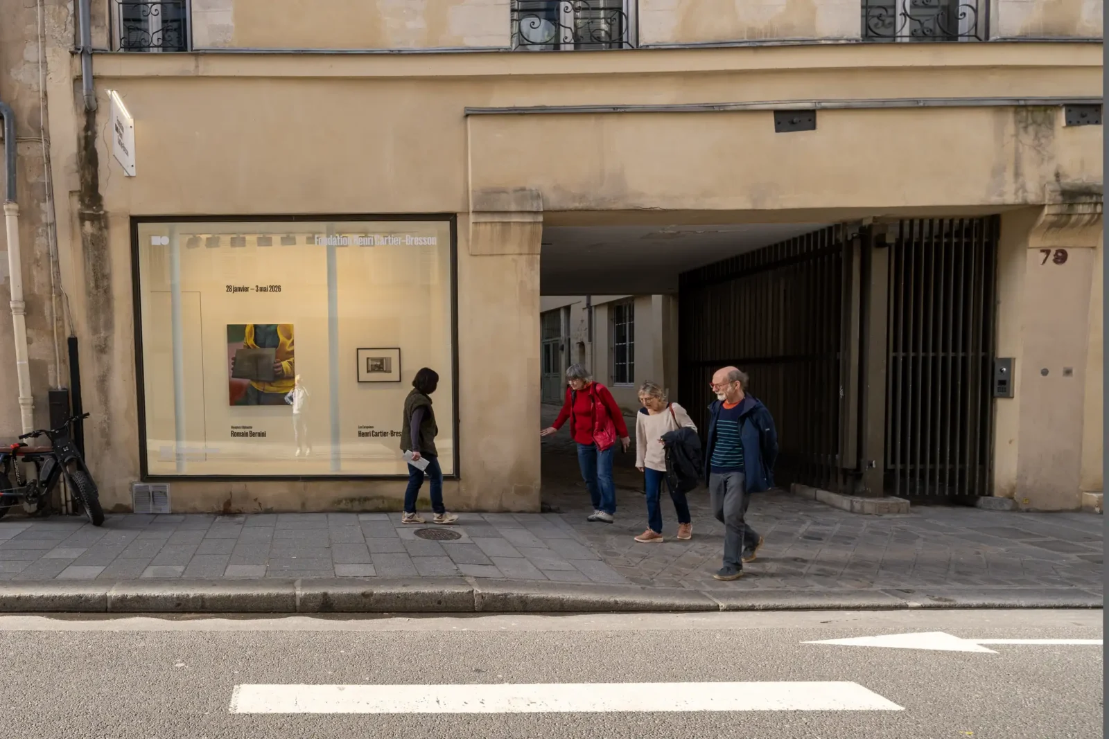 Des passants marchent devant la façade de la Fondation Henri Cartier-Bresson dans une rue parisienne.