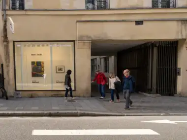 Des passants marchent devant la façade de la Fondation Henri Cartier-Bresson dans une rue parisienne.